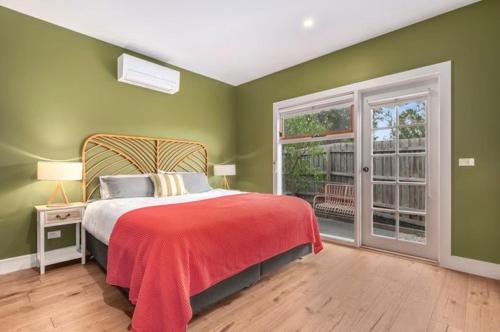 a bedroom with green walls and a bed with a red blanket at Peninsula Green Cottage for 14 guests in Capel Sound