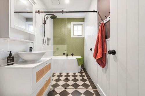 a white bathroom with a sink and a tub at Peninsula Green Cottage for 14 guests in Capel Sound