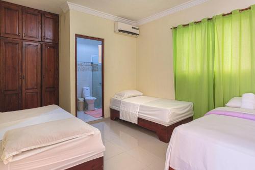 a bedroom with two beds and a green curtain at BNB Habitaciones Economicas - Cerca Aeropuerto Las Americas in La Viva