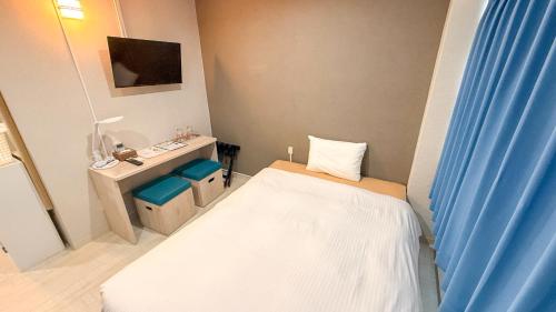 a small room with a bed and a desk at 還元ホテル 名護東江 in Nago
