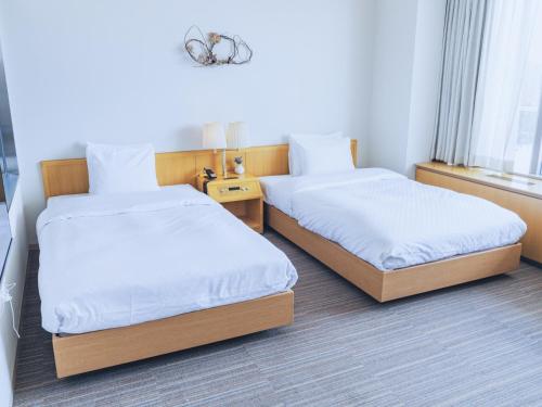 a hotel room with two beds and a window at Furano Hotel 富良野ホテル in Furano
