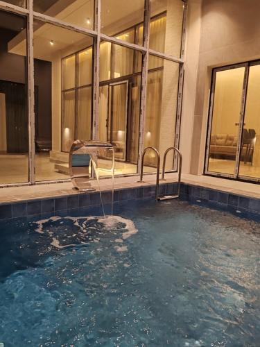 a swimming pool with two chairs in a building at شاليه اغصان الباحة in Al Baha