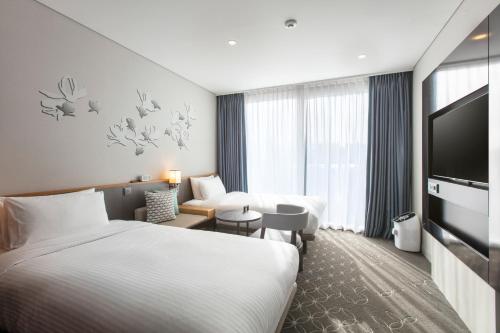a hotel room with two beds and a flat screen tv at Hotel Gracery Seoul in Seoul