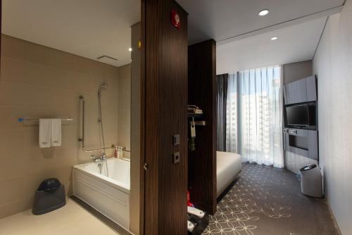 a bathroom with a tub and a sink and a bath tub at Hotel Gracery Seoul in Seoul