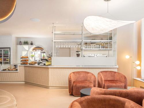 a restaurant with orange chairs and a counter with a counter at ibis London Earls Court in London
