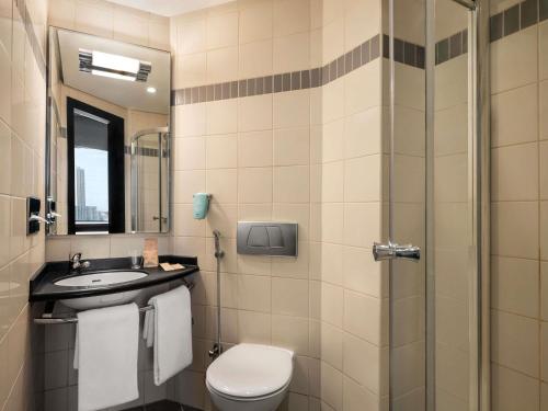 a bathroom with a toilet and a sink and a shower at ibis Sharq in Kuwait