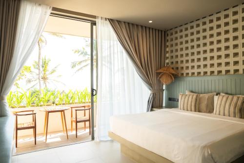 a bedroom with a bed and a balcony with a table at Petti Petti Beach Club- Mirissa in Mirissa