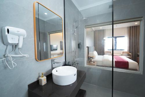 a bathroom with a sink and a mirror and a bed at Eden Luxury Hotel in Thái Bình