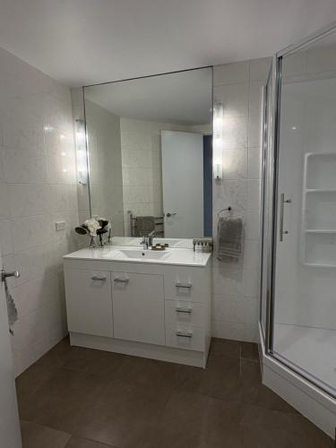 a white bathroom with a sink and a mirror at Apartment 303 Tauranga in Tauranga