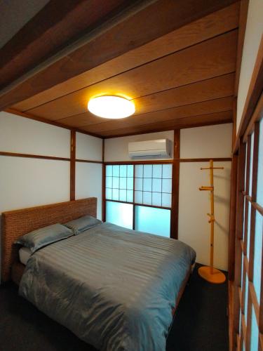 a bedroom with a bed and two windows at Nara House R2 in Kawagoe
