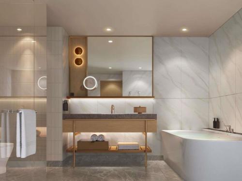 a bathroom with a sink and a tub and a mirror at Pullman Kuching in Kuching