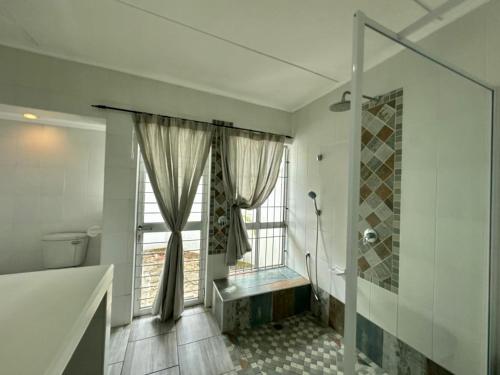 a bathroom with a shower and a toilet and a window at Turtle Sands Holiday Home in Richards Bay