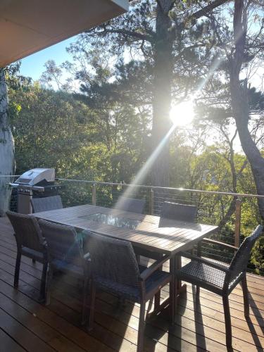 a table and chairs on a deck with the sun shining at Ficus Cottage - 3 Bed 2 Bath in Wentworth Falls