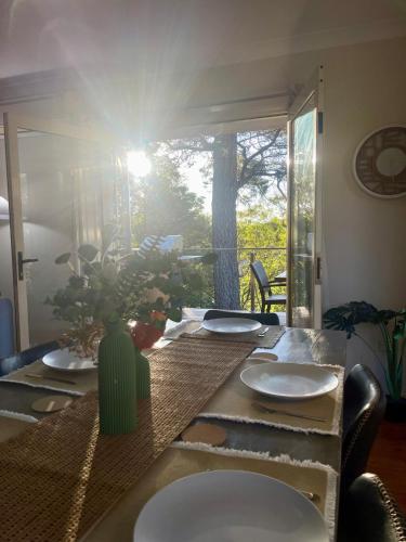 a table with plates and a vase on top of it at Ficus Cottage - 3 Bed 2 Bath in Wentworth Falls