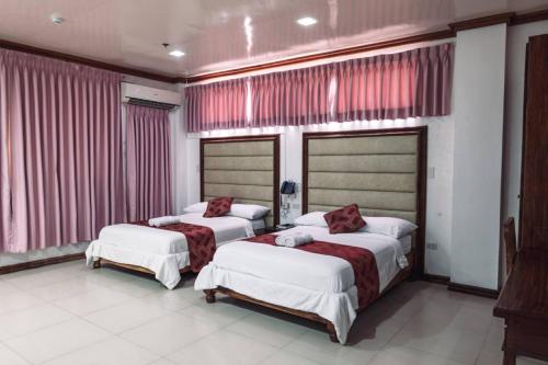 two beds in a room with red curtains at HOTELINDA Suites in Vigan