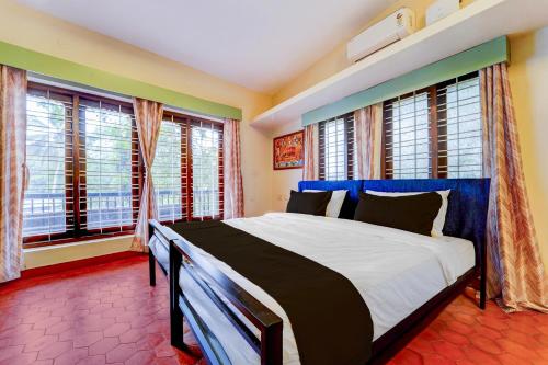 a bedroom with a large bed in front of windows at Super Hotel O CSIR Pappanamcode Formerly Ambadi Guest House in Poojapura
