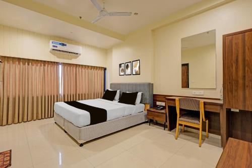 a bedroom with a bed and a desk and a mirror at Townhouse Vadodara Railway Station Road Formerly Hotel Raajpath in Vadodara