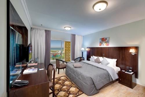 a bedroom with a bed and a desk and a television at Sharjah Carlton Hotel in Sharjah