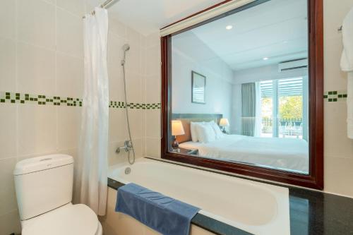 a bathroom with a tub and a bed and a mirror at Mondial Hotel Hue in Hue