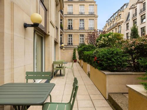 a patio with green tables and chairs on a building at Aparthotel Adagio Paris Haussmann Champs Elysées in Paris