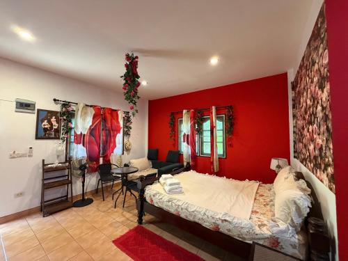 a bedroom with a red wall with a bed and a table at Rose bungalow at Ya Nui beach in Nai Harn Beach