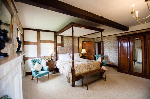 a bedroom with a large canopy bed and blue chairs at Soulton Hall in Wem