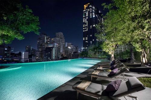 a swimming pool with lounge chairs and a city skyline at Hyatt Regency Bangkok Sukhumvit in Bangkok