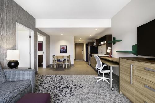 a living room and kitchen with a couch and a table at Home2 Suites by Hilton Stevens Point in Stevens Point