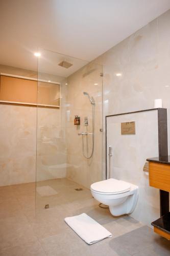 a bathroom with a toilet and a glass shower at Buddha Maya Garden by KGH Group in Rummindei