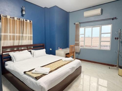 a blue bedroom with a bed and a window at Meesokxay Hotel Vang Vieng in Vang Vieng