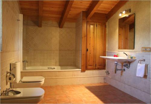 a bathroom with a toilet and a sink and a tub at Cal Miger in Tiurana