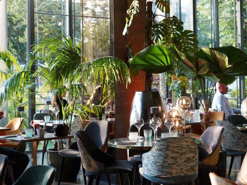 a restaurant with tables and chairs and plants at Pullman Paris Tour Eiffel in Paris