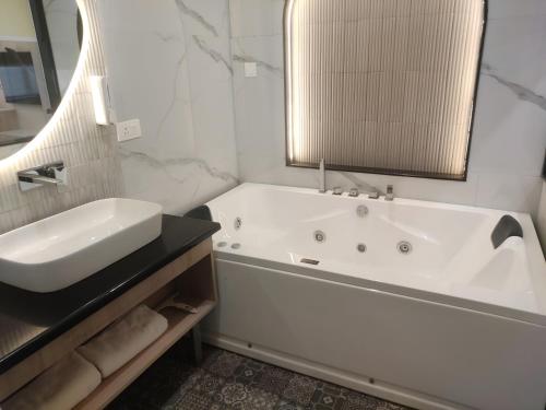 a white bathroom with a tub and a sink at Hotel Pallavi Grand in Panchkula