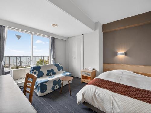 a hotel room with a bed and a chair and a window at Hitachi Ocean View HOTEL and RESORT in Hitachi