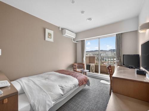 a hotel room with a bed and a desk and a window at Hitachi Ocean View HOTEL and RESORT in Hitachi