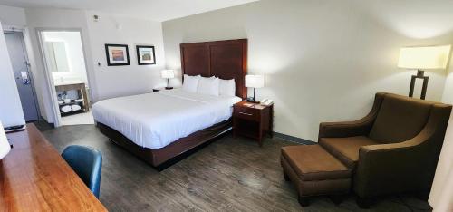 a hotel room with a bed and a chair at Comfort Inn Pensacola - University Area in Pensacola