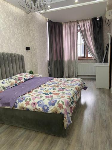 a bedroom with a bed with a floral comforter at Luxanda Samarkand in Samarkand