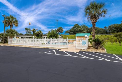 a parking lot with a white fence and palm trees at Quality Inn White Springs Suwanee in Live Oak