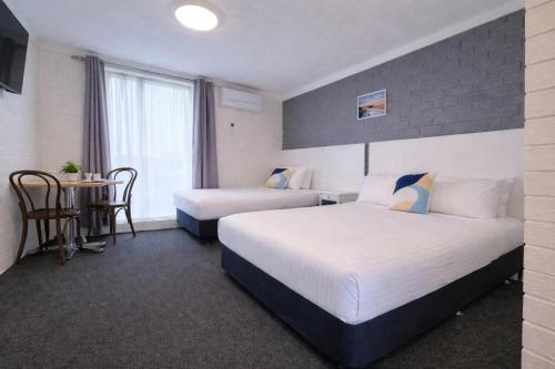 a hotel room with two beds and a table at Busselton Motel in Busselton