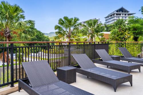 a row of chairs on a balcony with palm trees at Dreamland Suites - Walk to Dreamland Beach in Uluwatu