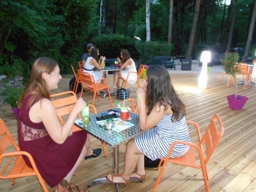 un groupe de femmes assises à une table sur une terrasse dans l'établissement Camping Saint James, à Guillestre