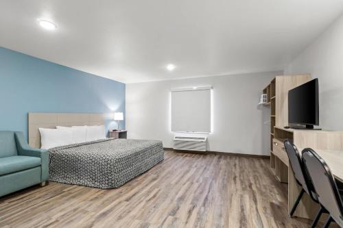 a bedroom with a bed and a tv and a couch at WoodSpring Suites Washington Meadowlands PA in Washington