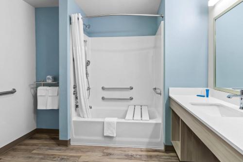 a bathroom with a shower and a tub and a sink at WoodSpring Suites Washington Meadowlands PA in Washington