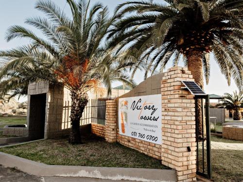 a sign in front of a building with a palm tree at Victory Towers in Bloemhof