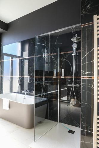 a black bathroom with a tub and a sink at Hôtel Séquoias in Ruy