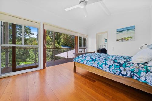a bedroom with a bed and a balcony with windows at Dragonflies on Billa in Point Lookout