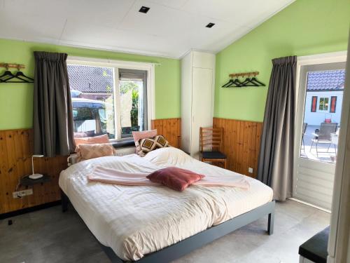a bedroom with a bed with green walls and a window at Vakantiepark de Bronzen Eik in Sellingen