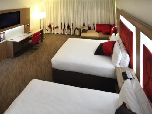 a hotel room with two beds and a television at Novotel Sydney West HQ in Rooty Hill