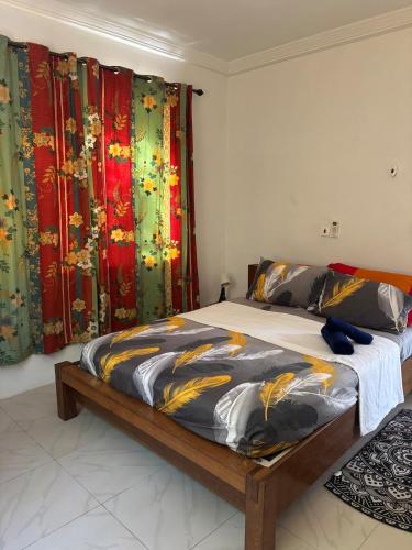 a bedroom with a large bed with colorful curtains at Rainbow Palace Apartment in Sekondi-Takoradi