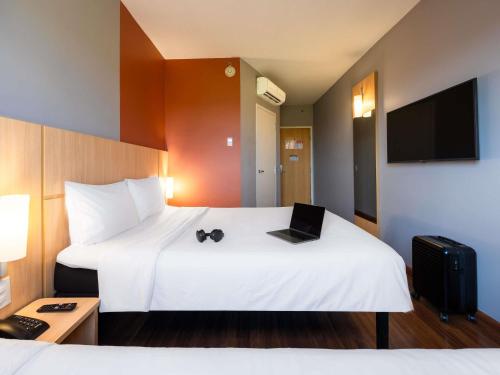 a hotel room with a bed with a laptop on it at ibis Ourinhos in Ourinhos